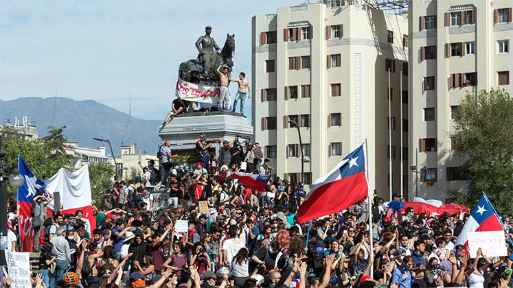Crowds of protesters in Santiago, Chile, surrounding a statue
