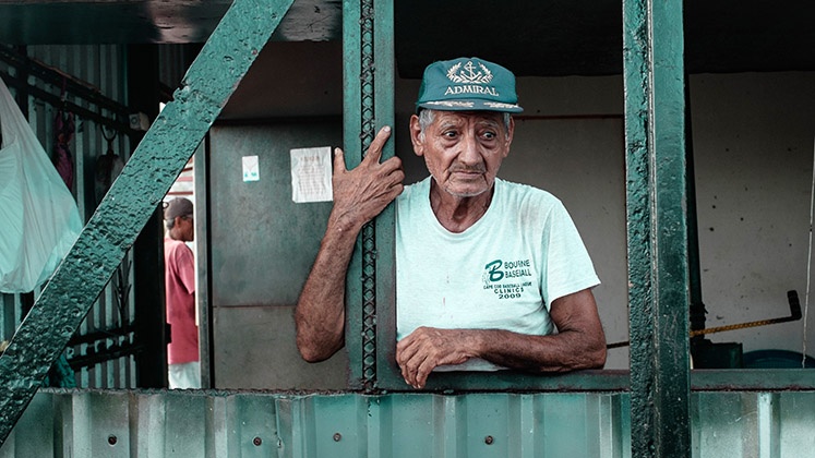An elderly man in La Libertad, El Salvador, holds on to a column while starting into the distance