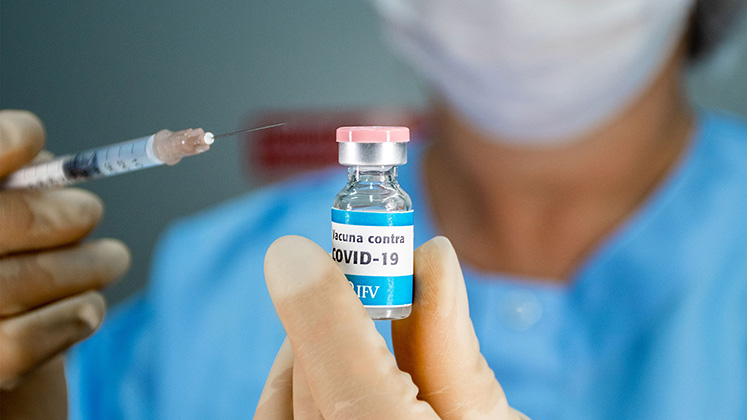 A Cuban scientist holds up a vial of Soberana II COVID-19 vaccine and a syringe