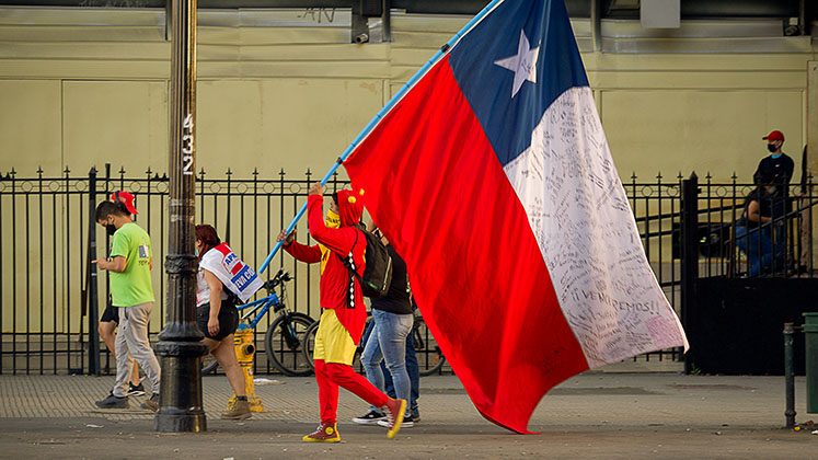 A man in fancy dress carries a huge Chilean flag during the social protests of 2020