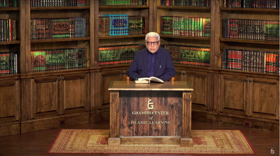 Javed Ahmad Ghamidi sitting at a desk with the Qur'an open in front of him.