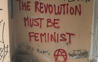 Graffiti in red on a wall: "The revolution must be feminist" and anarchist A sign