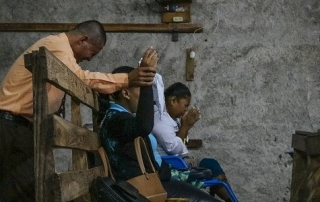 People praying on a wooden bench