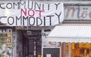 A shop front with home-made banner above with text "Community not commodity"