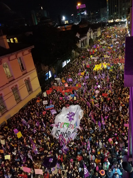 Image of a street filled with people for the Women's March in Istanbul, with a large white feminist banner held up
