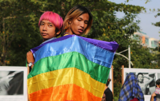 Picture of two young people holding rainbow flag