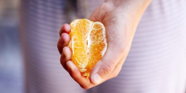 Orange half, cupped in a woman's hand (suggestive in shape)