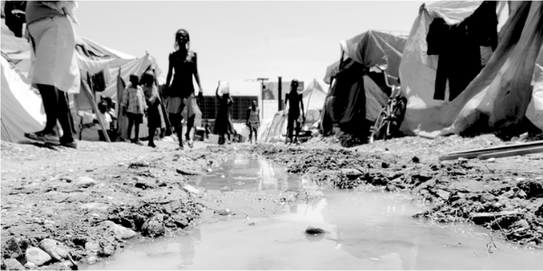 Photo of a camp in Port au Prince, focussed on stagnant water on the ground