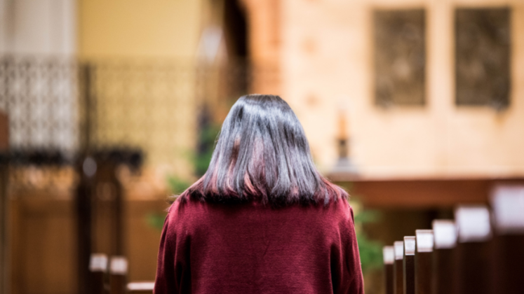 Woman bowing her head in prayer in church