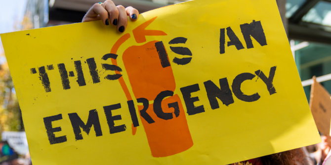 Yellow sign with image of orange fire extinguisher reading 'This is An Emergency'