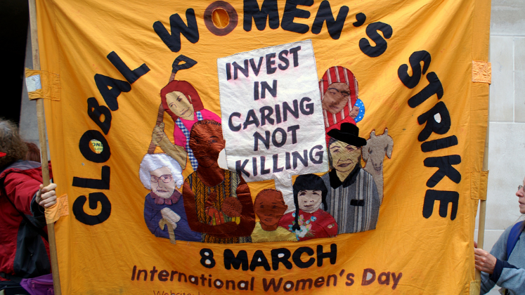 Global Women's Strike banner reading 'Invest in Caring Not Killing' 