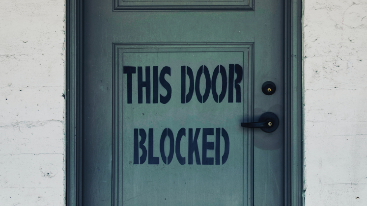 Door with sign reading 'This Door Blocked' 