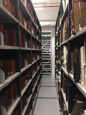 Archival boxes stacked in two floor to ceiling shelves in the LSE basement