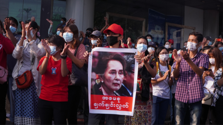 Protestors holding signs defending Aung San Suu Kyi