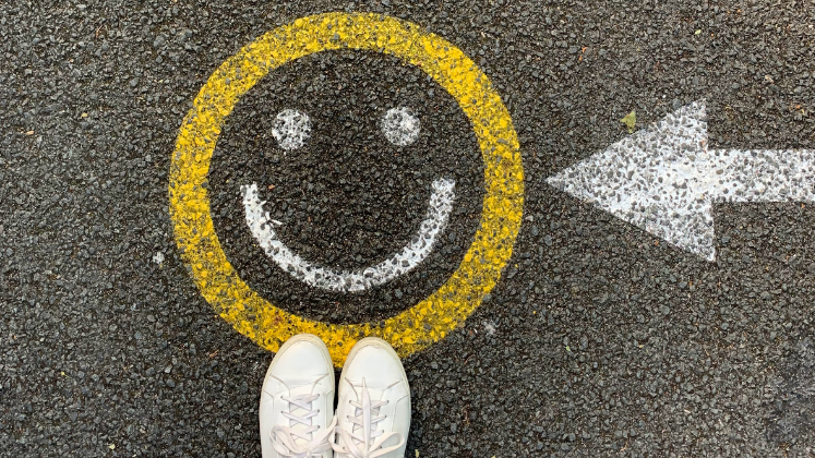 Feet standing on smiley face on ground with an arrow pointing to it