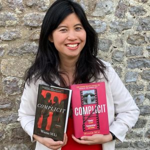 Author Winnie M Li holding the US and UK versions of Complicit
