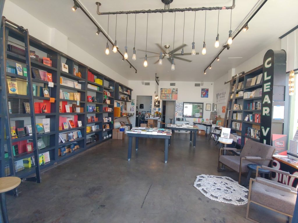 Interior of Deep Vellum Books, featuring blue bookshelves and brown chairs