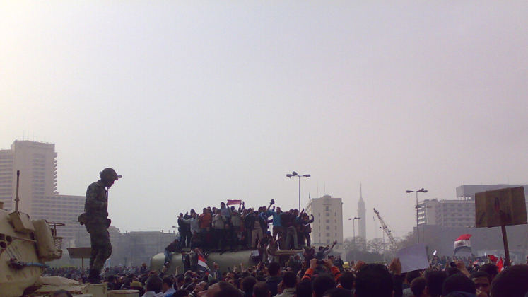 Soldier on tank in Tahrir Square, Egypt, with group of protestors on tank in background