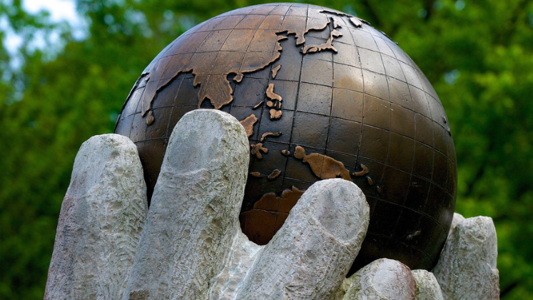 Stone hands holding up a stone globe