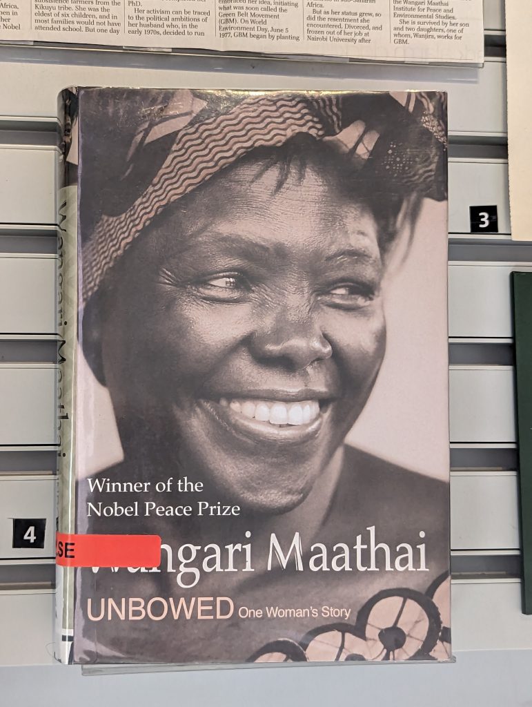 A photograph of hardback book with the title 'Unbowed: My autography, Wangari Maathai'. Behind the title is a photograph of Wangari Maathai smiling.
