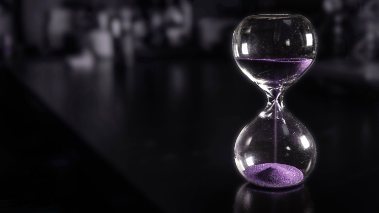Hourglass on table with purple sand
