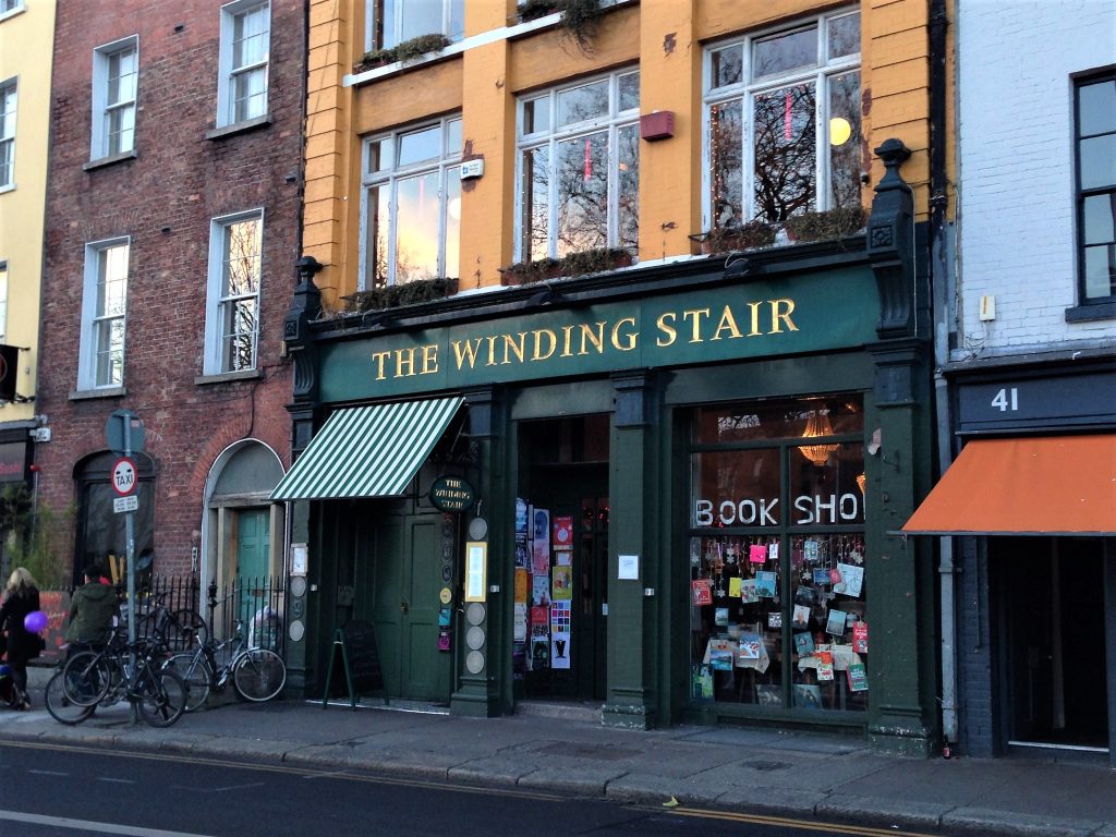 Image of the Wining Stair Bookshop on Ormond Quay, Dublin, a green shop front with a pavement in front of it.