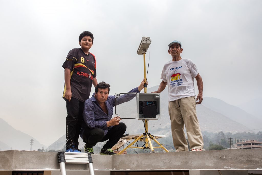 Members of a local disaster risk reduction network with their solar powered early warning monitoring device [https://practicalaction.org/knowledge-centre/resources/monitoring-rainfall-for-early-warning-perus-ingenious-solutions/] near Lima, Peru. Photo by Practical Action. 