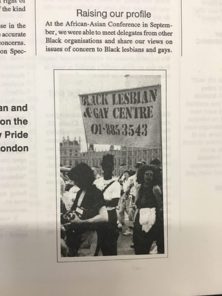A clipping from a newsletter with a photograph of BLGC members at a protest in what looks like Parliament Square in London. They are carrying a BLGC banner.