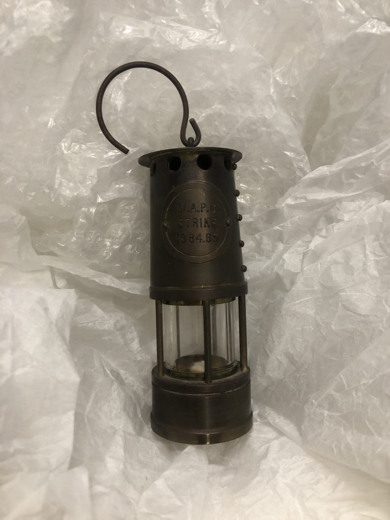 A hand held lamp with "WAPC Strike 1984-85" engraved on it. 