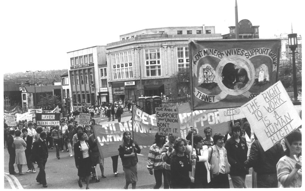 A march with banners that read "The Right To Work Is A Human Right" and "Kent Miners Wives Support Group". 