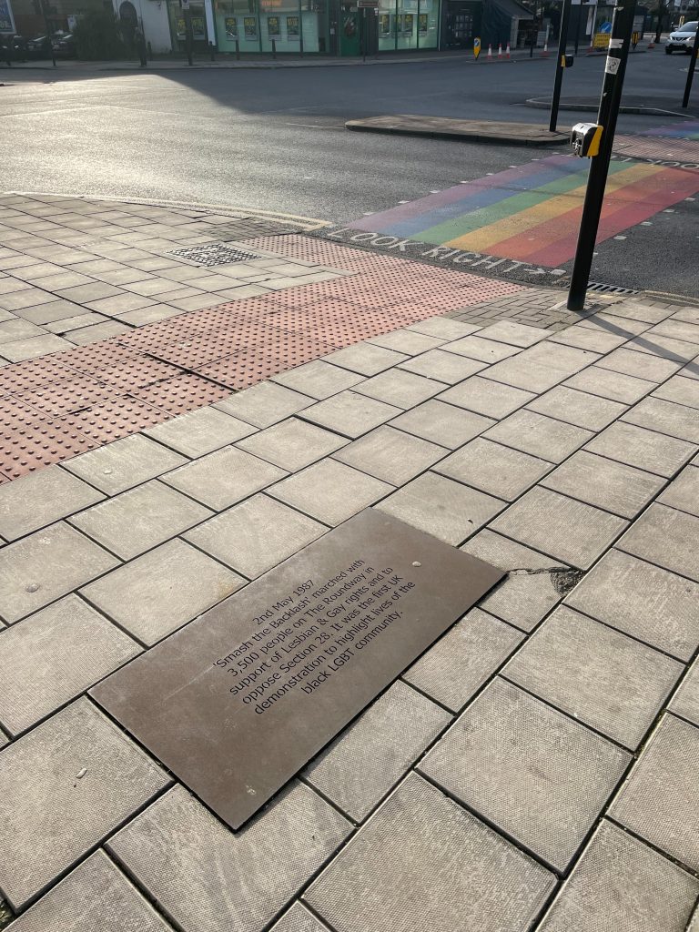 A view of the pavement, plaque, road and rainbow crossing in Haringey. 