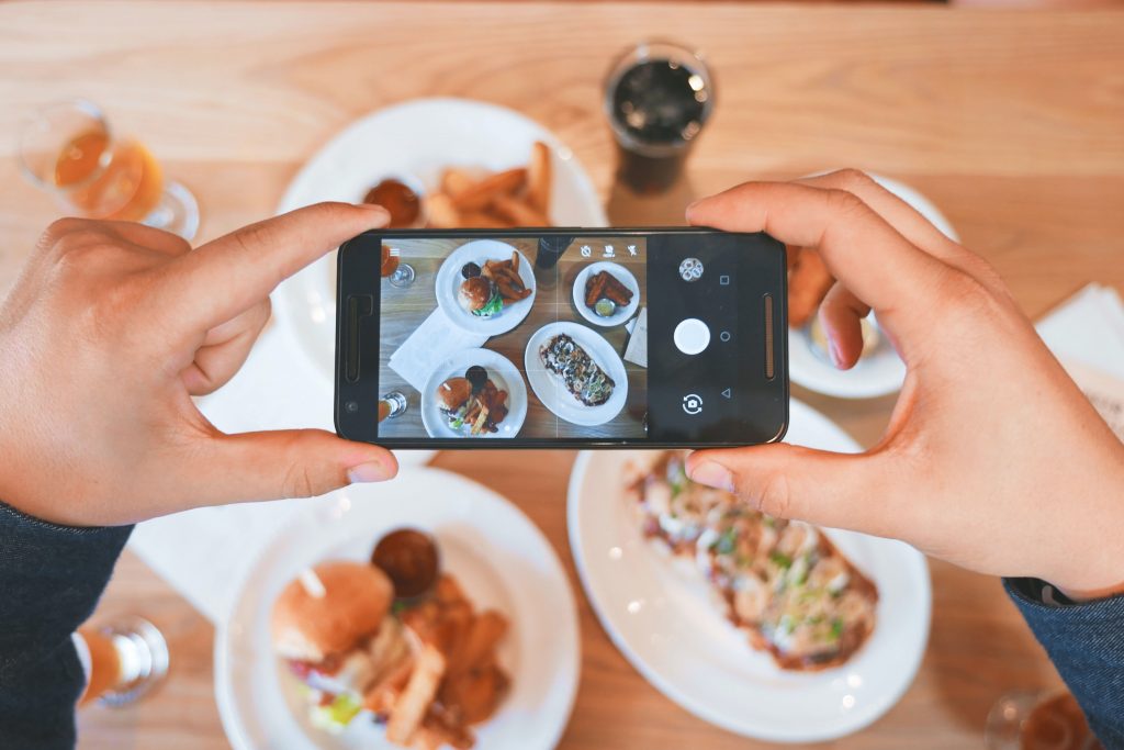 Smartphone being used to take picture of aesthetically pleasing selection of food.