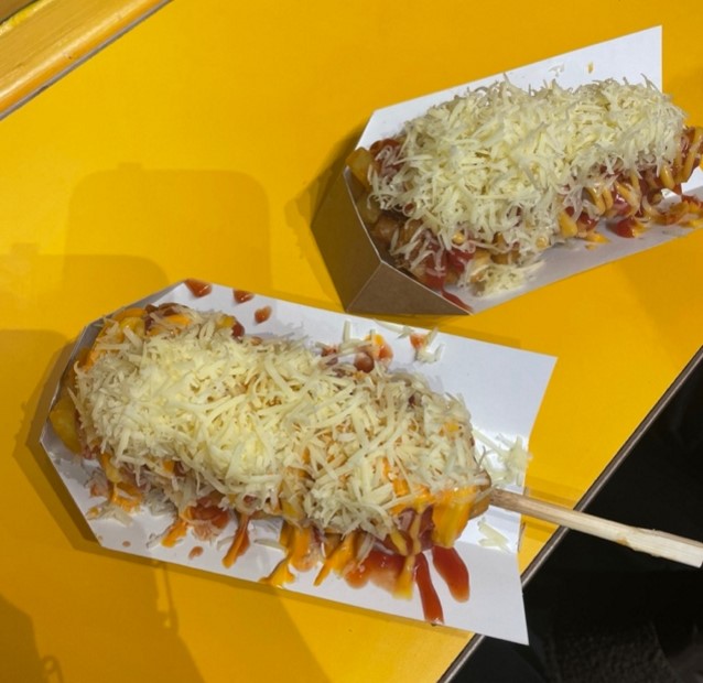 two korean style corn dogs covered in sauce and cheese plus other toppings from the restaurant Bunsik
