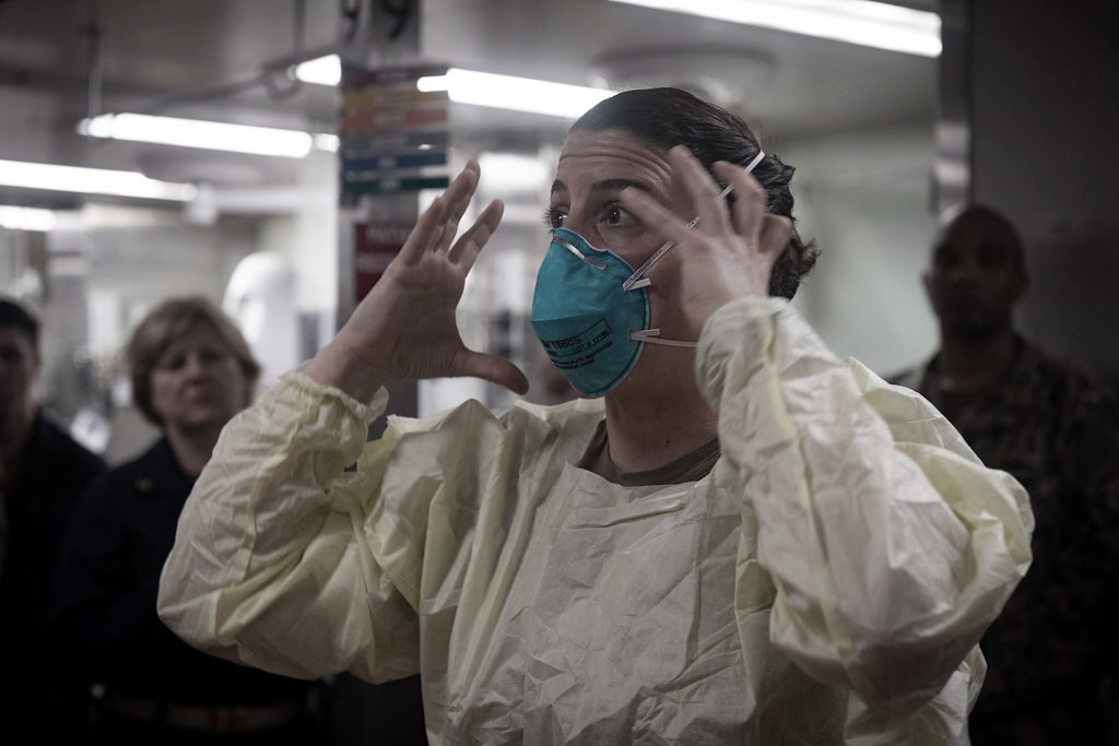 A woman in a medical gown and wearing a face mask